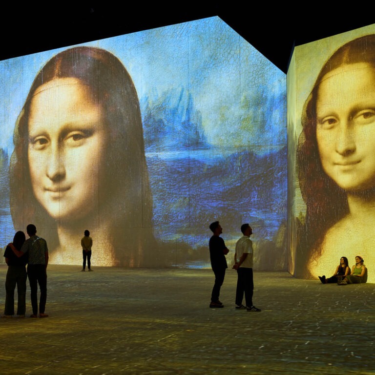 People viewing large images of the Mona Lisa projected on walls